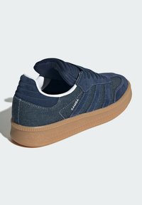 Sneakers in suede blu navy con dettagli in denim, dotati di suola in gomma beige e fodera bianca. Design con tre strisce sul lato e logo sul tallone.