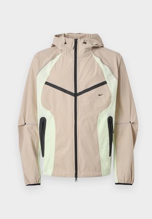 Μπεζ και ανοιχτοπράσινο μπουφάν με κουκούλα, μαύρο κάθετο φερμουάρ μπροστά, τσέπες με φερμουάρ στα πλάγια και μικρό μαύρο λογότυπο της Nike στο στήθος.