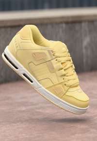 Baskets jaunes avec une texture en daim lisse, présentant des détails perforés, des accents texturés et une semelle blanche avec un amorti d'air.
