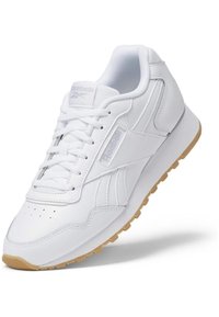 Zapatillas deportivas blancas con parte superior de cuero suave, puntera perforada y suela de goma. Presentan cordones y un discreto detalle de marca.