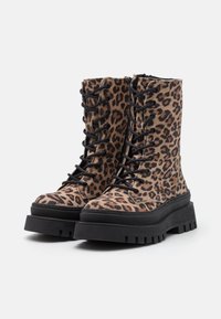 Leopardmønster ankelstøvler med en suedetekstur, med svarte snøringer, en kraftig svart såle, og en glidelåsdetalj langs siden.