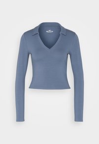 Långärmad, kort croppad blå V-ringad skjorta med krage, uppvisad på en slät vit bakgrund, märkt Hollister California.