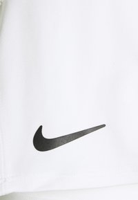 Tela atlética blanca con una textura lisa que presenta un logo del swoosh de Nike en negro en el lado izquierdo. Diseño minimalista, sin patrones adicionales.