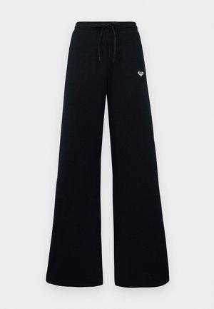 Zwarte wijde broek met ribbeltextuur, elastische tailleband en trekkoord. Bevat een klein wit logo aan de bovenlinkerkant.