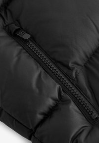 Sección de chaqueta de plumas negra con un zipper texturizado y tela suave. Forma rectangular con secciones de aislamiento esponjoso.