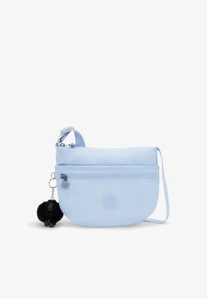 Bolso bandolera de nylon de color azul claro con forma redondeada, cremallera superior, bolsillo frontal y un charm de pompón negro. Presenta un detalle de logo.