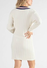 Cable-knitted sweater dress in gebroken wit, met lange mouwen, een geribbelde zoom en een marineblauwe kraag met rode en witte strepen.