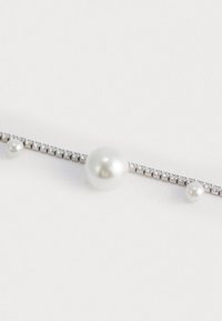 Bracciale in perle e cristalli con tre grandi perle e una fila di piccoli cristalli su una catena metallica, con una finitura liscia e lucida.