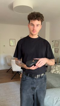 Must mustris must pruunistäramasses rongi ja kuldne logo, hoiab must särk inimesel, asetatud heledasse, kaasaegsesse elutuppa.