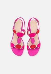 Fuchsia suede sandals with a slingback design; features decorative, multi-colored oval accents and gold-tone hardware. Flat heel.