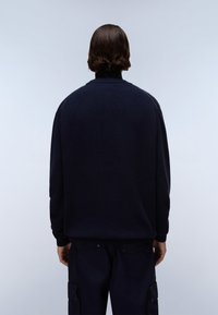 Dunkelblauer Pullover mit lockerer Passform, gerippten Bündchen und rundem Ausschnitt. Glatte Textur, minimale Details und keine sichtbaren Logos.