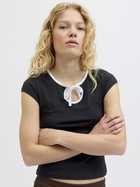 Camiseta negra corta con mangas cortas, que presenta un cuello blanco y un detalle de lazo en el escote. Tejido suave y diseño ajustado.