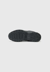 Schwarze Sneaker-Sohle mit strukturiertem Gummi für Traktion, ausgestattet mit einem multidimensionalen Muster und einem Logodetail an der Seite.