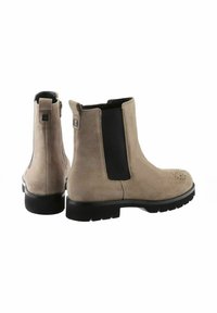 Stivaletti in suede beige alla caviglia con pannelli laterali elastici, punta arrotondata e perforazioni decorative; presentano una suola in gomma nera testurizzata bassa.