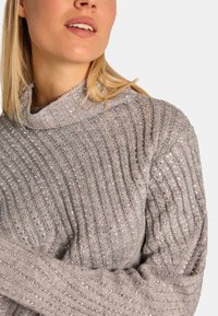 Grijze gebreide trui met een geribbelde structuur, voorzien van sprankelende accenten. Het heeft een col en lange mouwen en toont een getailleerd silhouet.