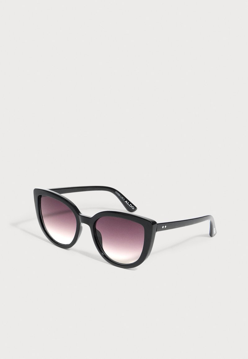 Lunettes de soleil œil-de-chat noires avec des verres teintés en dégradé violet reposant sur une surface gris clair.
