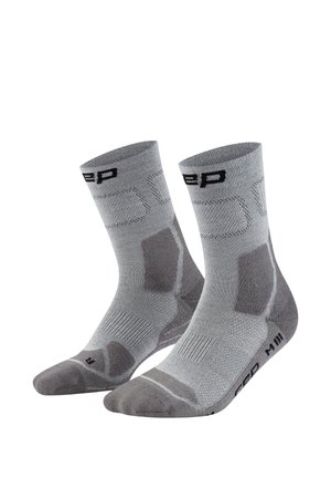 Grey athletic mid-calf socks with reinforced heel and toe areas, textured arch support, and black branding near cuffs and soles.