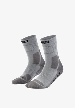 Grey athletic mid-calf socks with reinforced heel and toe areas, textured arch support, and black branding near cuffs and soles.