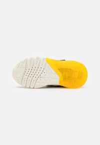 Suela de zapatilla con una base de goma blanca texturizada, que presenta una sección de talón transparente amarilla y patrones de tracción multidireccional.