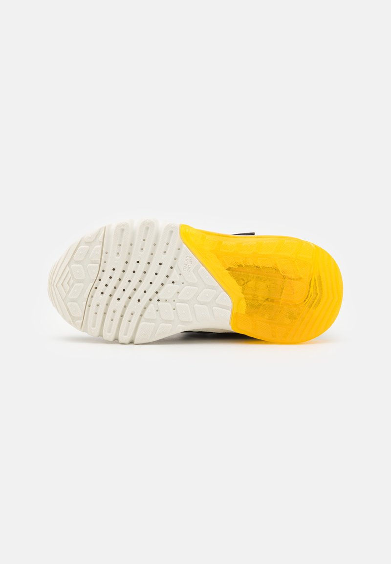 Semelle de sneaker avec une base en caoutchouc blanc texturé, présentant une section de talon transparente jaune et des motifs de traction multidirectionnels.