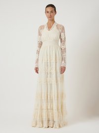 Largo vestido de marfil con mangas largas transparentes, intrincados bordados florales y tela de encaje en capas; cuenta con un escote en V y una falda fluida.
