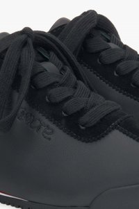 Czarne sportowe buty z gładką skórzaną cholewką z zamszowymi akcentami, okrągłymi sznurowadłami i teksturowaną gumową podeszwą.