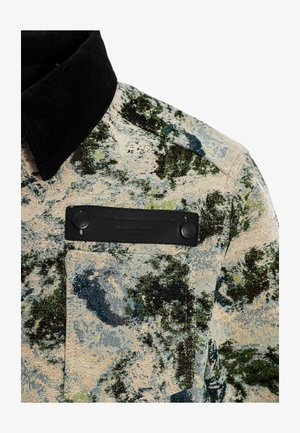 Americana con cuello en tejido texturizado con un patrón botánico en verdes y azules, que presenta un bolsillo de parche negro y botones.