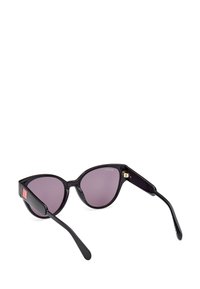 Gafas de sol negras en forma de ojo de gato con lentes morados, que presentan un acabado brillante, bordes del marco esculpidos y un pequeño acento de logo rojo en la patilla.
