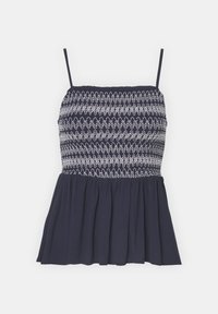 Nautičko plavi peplum top s trakama, koji ima smocked korzet i bijele cik-cak šavove za dodatnu teksturu i detalj.