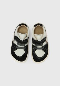 Μαύρα και κρεμ αθλητικά παπούτσια με ιμάντες βέλκρο, σουέτ και συνθετικό υλικό, στρογγυλεμένη μύτη,  λευκή καουτσούκ σόλα και αντίθετες ραφές.