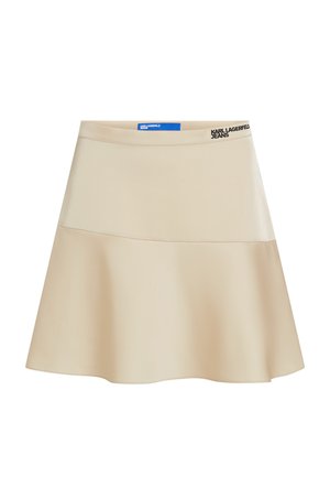 Beige színű, bővülő szoknya sima anyagból, széles derékrésszel, amelyen fekete logó díszítés található. A dizájn egyszerű, A-vonalú, alkalmi viseletre ideális.