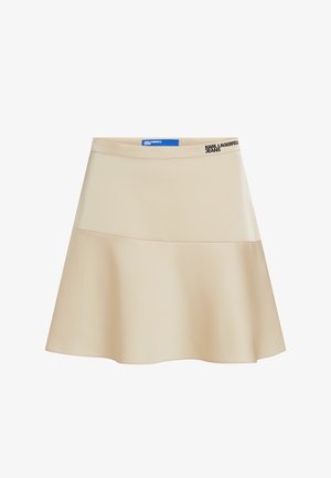 Beige színű, bővülő szoknya sima anyagból, széles derékrésszel, amelyen fekete logó díszítés található. A dizájn egyszerű, A-vonalú, alkalmi viseletre ideális.