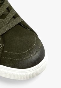 Zapatillas de ante verde con una parte superior texturizada, puntera redonda, suela de goma blanca y costuras tonales. Los cordones están entrelazados en un patrón grueso.