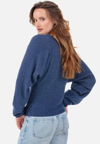 Blauer gestrickter Pullover mit langen, voluminösen Ärmeln und tailliertem Schnitt. Hergestellt aus weichem Stoff mit strukturierter Oberfläche. Lässiges Design.