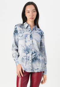 Camicia con bottoni caratterizzata da una stampa floreale blu e bianca e palme su un tessuto morbido. Maniche lunghe e design con colletto standard.