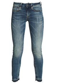 Slim jeans i medelblå denim med blekta områden, fem fickor, metallknapp och dragkedja, samt råa fållar.