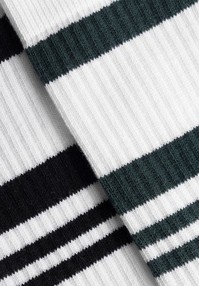 Gros plan sur un tissu côtelé avec des rayures horizontales noires et blanches superposé à un tissu côtelé avec des rayures vert foncé et blanches.