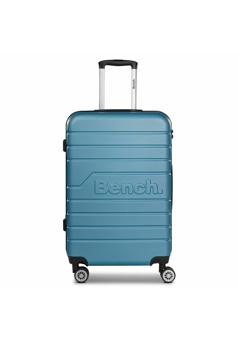 Harde koffer in teal met horizontale ribbels, zwarte handvatten en vier wielen voor mobiliteit. Bevat het reliëflogo "Bench."
