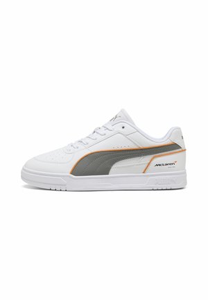 Baskets basses blanches Puma avec bande latérale grise, bordure orange et logo McLaren Racing sur la partie du talon, vues de l'extérieur.