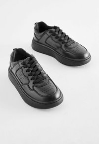 Svarta lädersneakers med en kraftig sula, utrustade med perforerad detaljering, texturerade skosnören och en rundad tådesign.