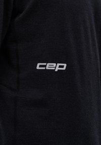 Top sportivo nero con una texture liscia, caratterizzato da un logo "cep" grigio sul lato sinistro inferiore e dettagli di cucitura sottili.