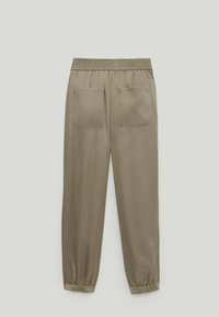 Lyse olivengrønne sweatpants med elastisk talje, to baglommer og elastiske manchetter ved anklerne. Glat stofstruktur.