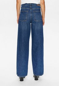 Korkeavyötäröiset siniset leveälahkeiset farkut, joissa on kaksi takataskua ja siisti helma, valmistettu kestävästä farkkukankaasta.