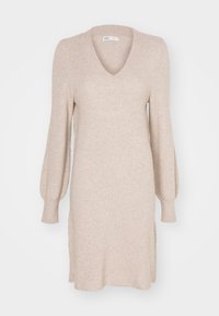 Robe en tricot beige avec un décolleté en V, de longues manches bouffantes et des fentes sur les côtés. Texture douce avec une coupe légèrement ample.