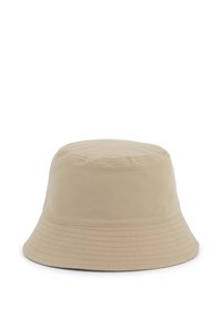 Chapeau seau beige avec une couronne structurée et un large bord flexible. Fait en tissu lisse, il présente des coutures le long du bord.