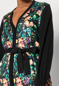 Gebloemd cardigan in zwart en levendige kleuren, met een diepe V-hals, lange mouwen en een gestrikt ceintuur op de taille.