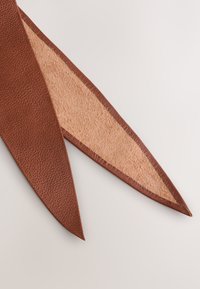 Brown leather triangular design with a textured surface and smooth beige interior. Edges are neatly stitched, showing quality craftsmanship.