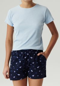 Jasnoniebieska, prążkowana koszulka z krótkim rękawem w połączeniu z granatowymi szortami z motywem motyli i elastycznym paskiem.