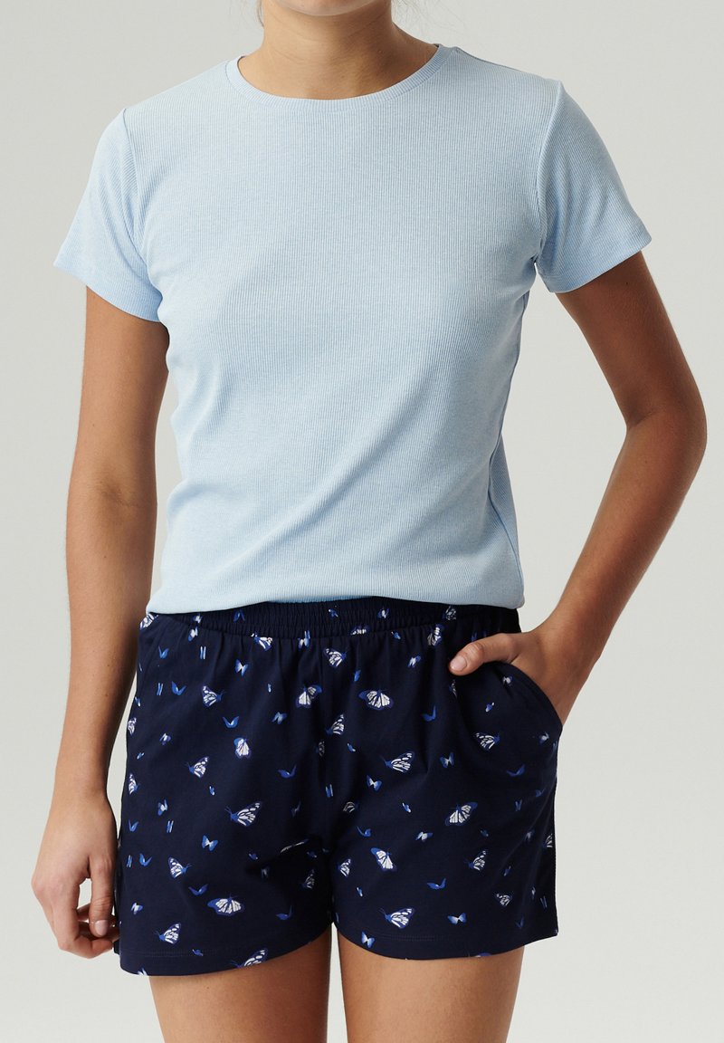 Jasnoniebieska, prążkowana koszulka z krótkim rękawem w połączeniu z granatowymi szortami z motywem motyli i elastycznym paskiem.