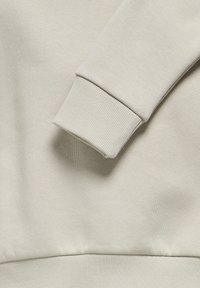 Lichtgrijze sweatshirtstof met een ribbelboord en zoom. Het materiaal heeft een zachte textuur en een gladde afwerking.